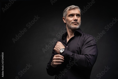 Middle-aged good looking man posing in front of a black background with copy space. photo