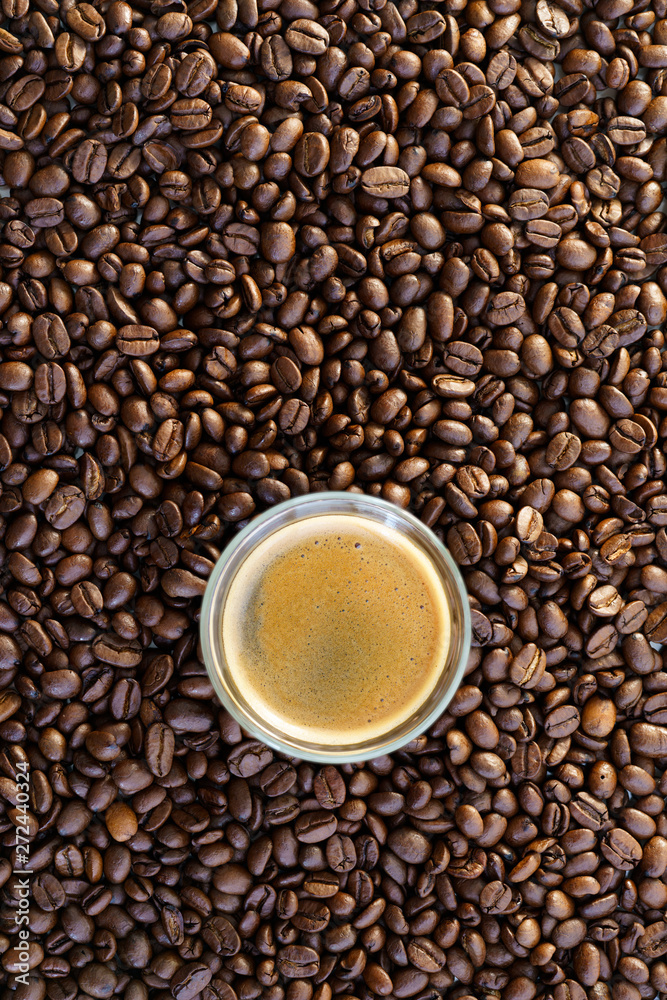 Espresso shot on a table filled with roasted coffee beans. High resolution Espresso shot on a table filled with roasted coffee beans. High resolution