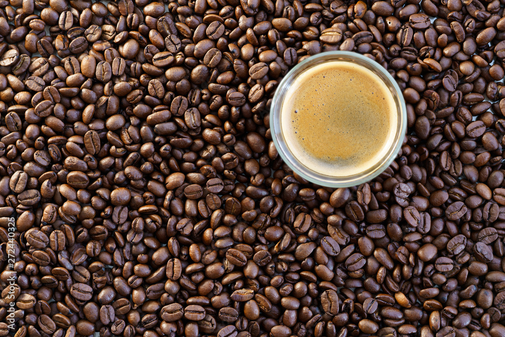 Espresso shot on a table filled with roasted coffee beans. High resolution Espresso shot on a table filled with roasted coffee beans. High resolution