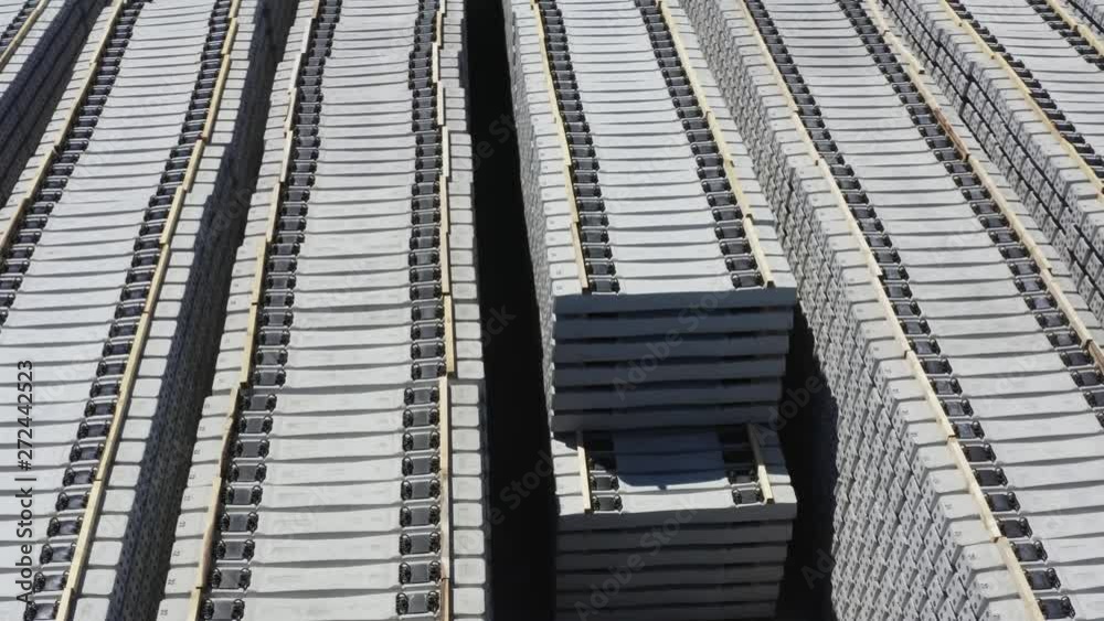 Rotating drone shot above many stacks of grey train sleepers, on a sunny day Rotating drone shot above many stacks of grey train sleepers, on a sunny day