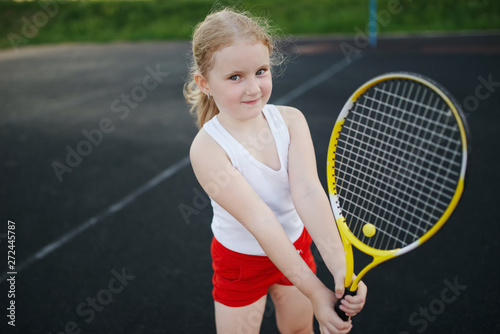 happy girl plays tennis on court outdoors
