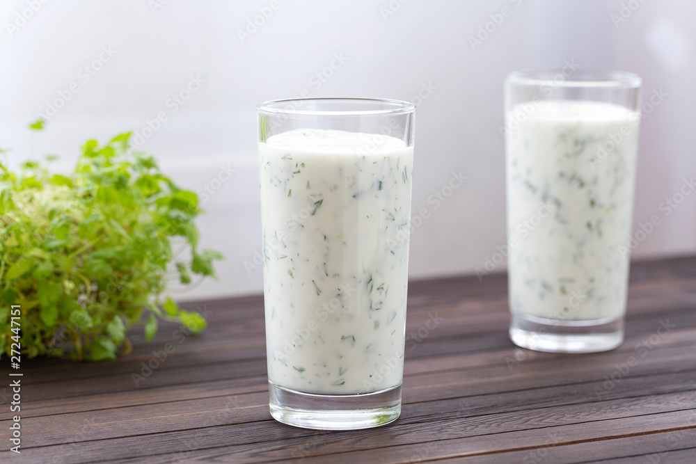 Fresh homemade yogurt (kefir, ayran) in glass with herbs. Ayran, homemade yogurt drink with herbs and cucumbers - healthy summer refreshing cold drink. Probiotic fermented dairy drink. Healthy food. Fresh homemade yogurt (kefir, ayran) in glass with herbs. Ayran, homemade yogurt drink with herbs and cucumbers - healthy summer refreshing cold drink. Probiotic fermented dairy drink. Healthy food.