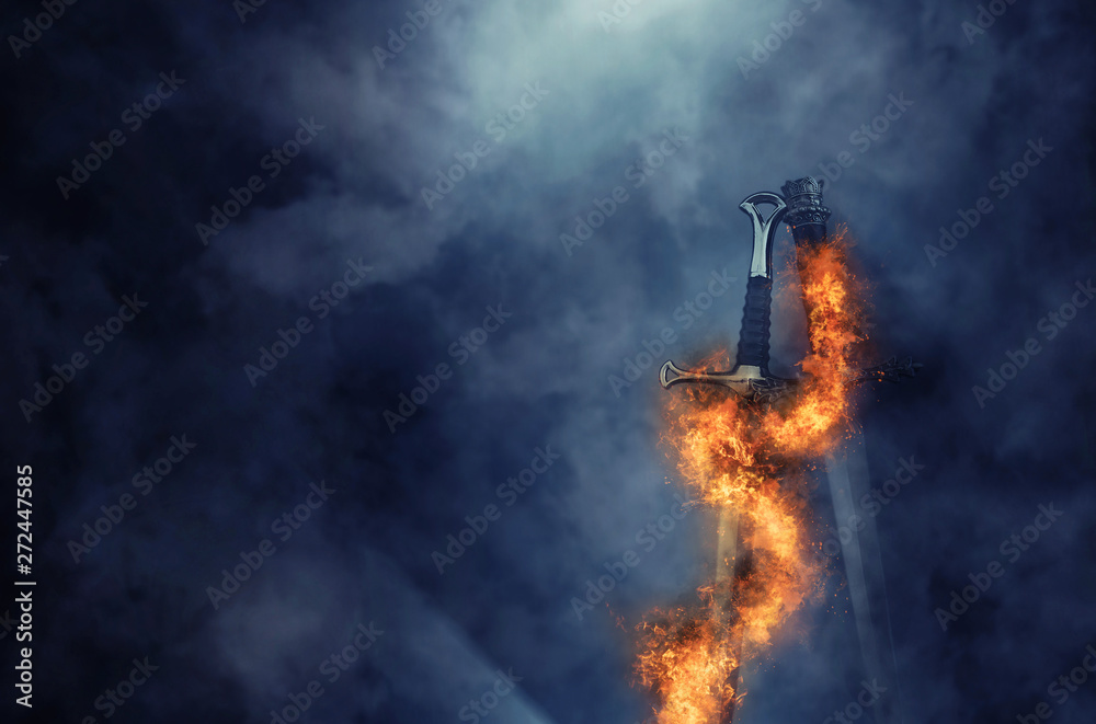 mysterious and magical photo of silver sword with fire flames over Gothic black background. Medieval period concept
