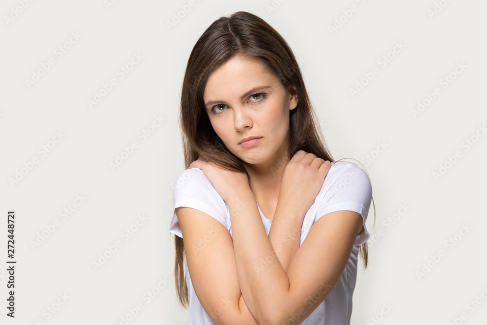Offended sad millennial girl pose over grey studio background Offended sad millennial girl pose over grey studio background