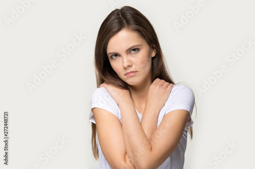Offended sad millennial girl pose over grey studio background
