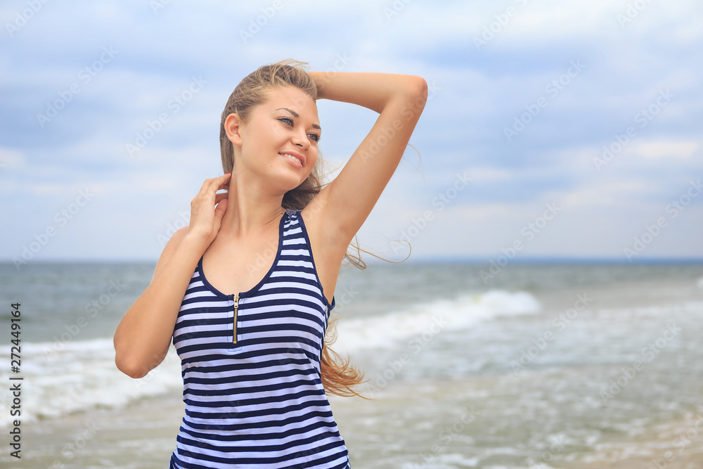 portrait of a beautiful happy young girl on the beach in a striped t-shirt, hair fluttering in the wind portrait of a beautiful happy young girl on the beach in a striped t-shirt, hair fluttering in the wind