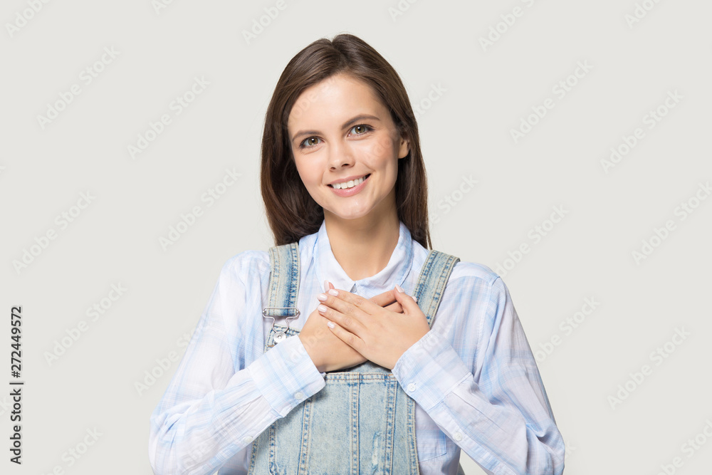 Attractive young woman holding hand on heart feels gratitude Attractive young woman holding hand on heart feels gratitude