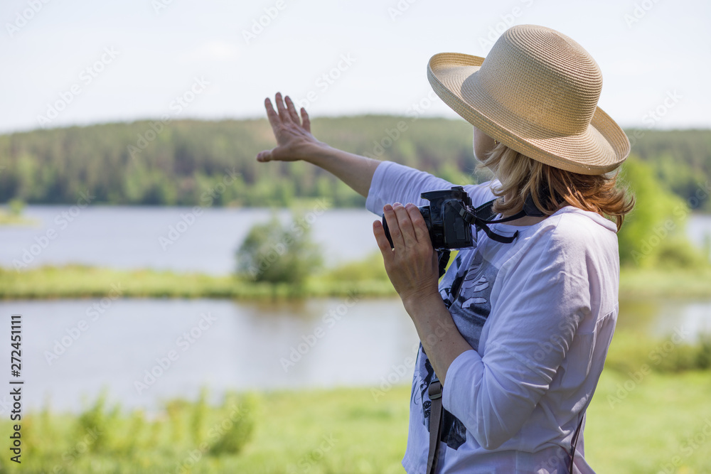 An elderly woman with a camera taking pictures of nature and enjoying life.