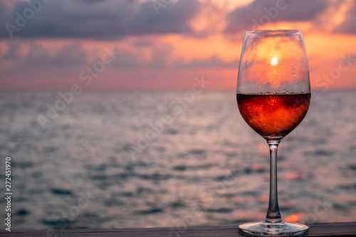 A glass of red wine on sunset background at the Maldives © Attaphon