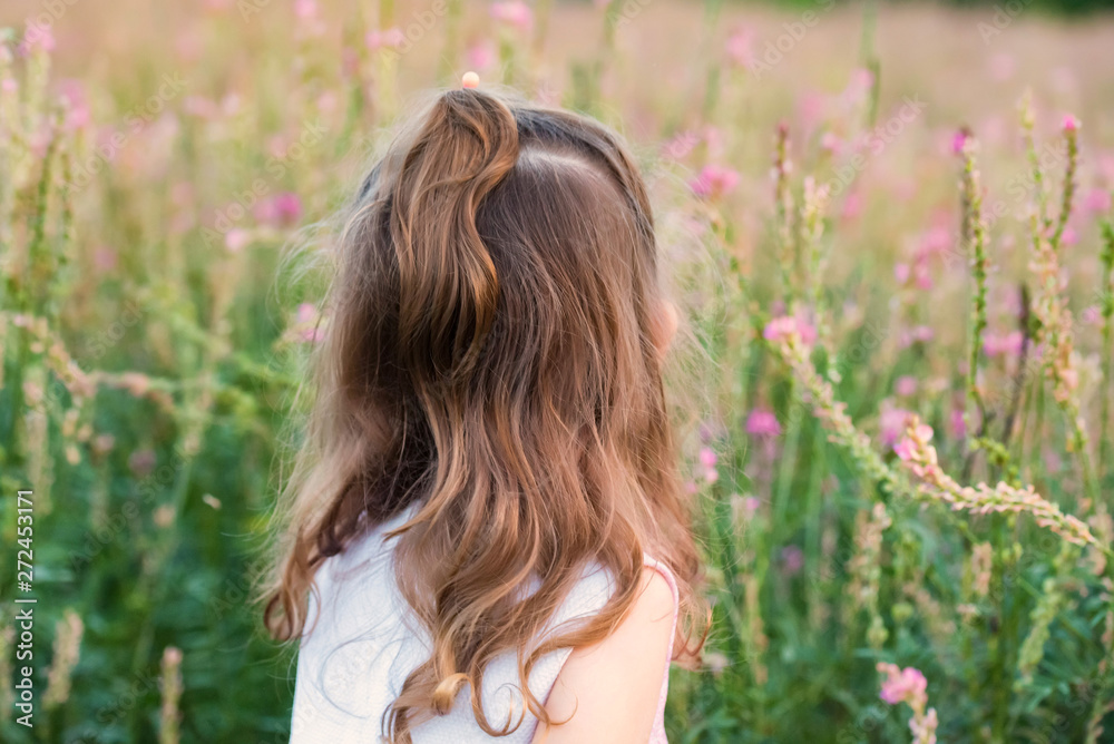 Back view cute baby girl outdoors in green field. Child portrait Back view cute baby girl outdoors in green field. Child portrait