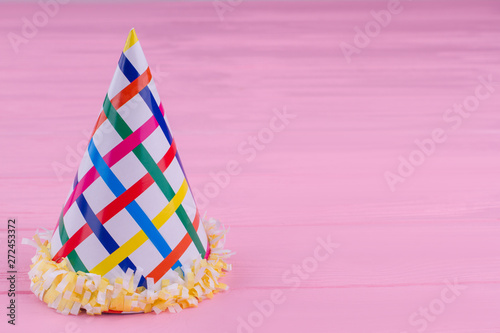 Paper cone hat for Birthday celebration. Cardboard party cap on color background with copy space. Birthday greeting card.