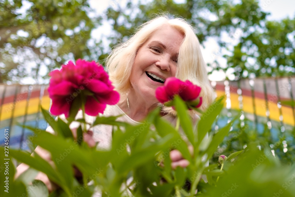 happy senior european woman with flowers blooming at summer garden happy senior european woman with flowers blooming at summer garden