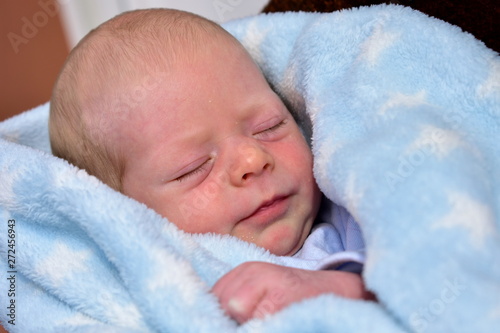 Newborn baby with a blue blanket. Blonde boy.