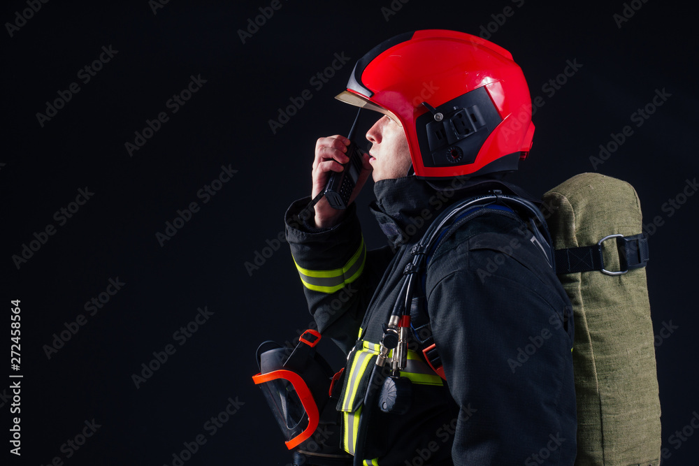 portrait strong fireman in fireproof uniform holding an ax in his hands black background studio