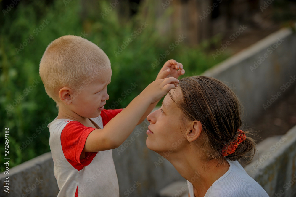 Fototapeta premium Country boy gently hugs beautiful mother. child is happy in village on vacation with mom