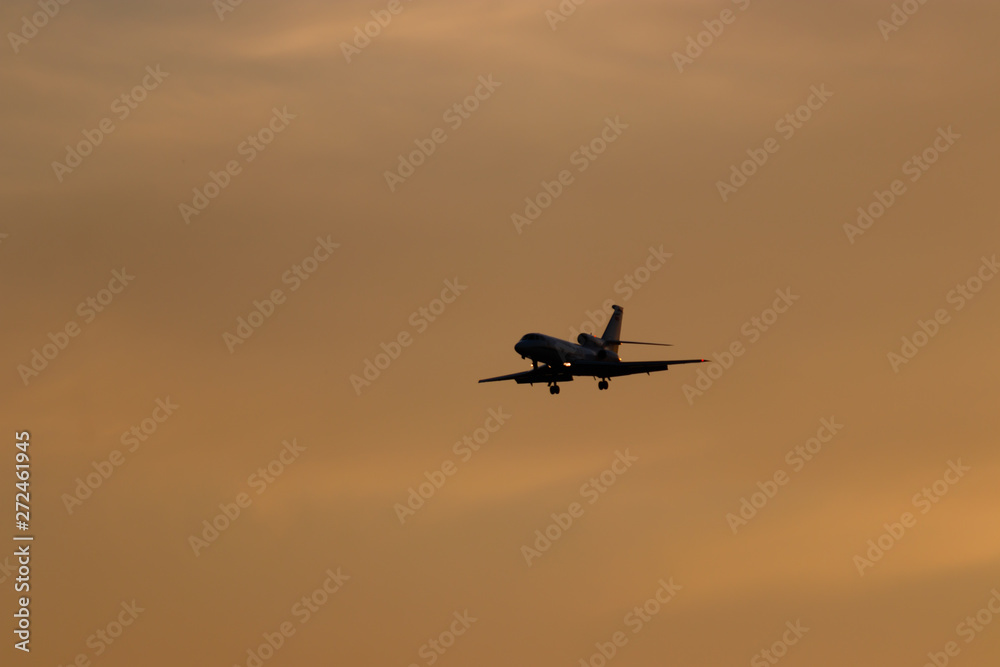 Plane preparing for landing with colorful sky at sunset