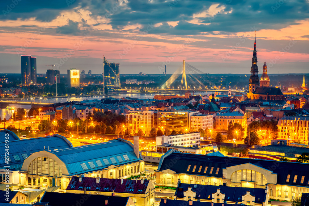 Fototapeta premium Beautiful aerial panorama of Riga center and Vansu bridge over Daugava river during amazing sunset. View of illuminated Riga city, capital of Latvia.