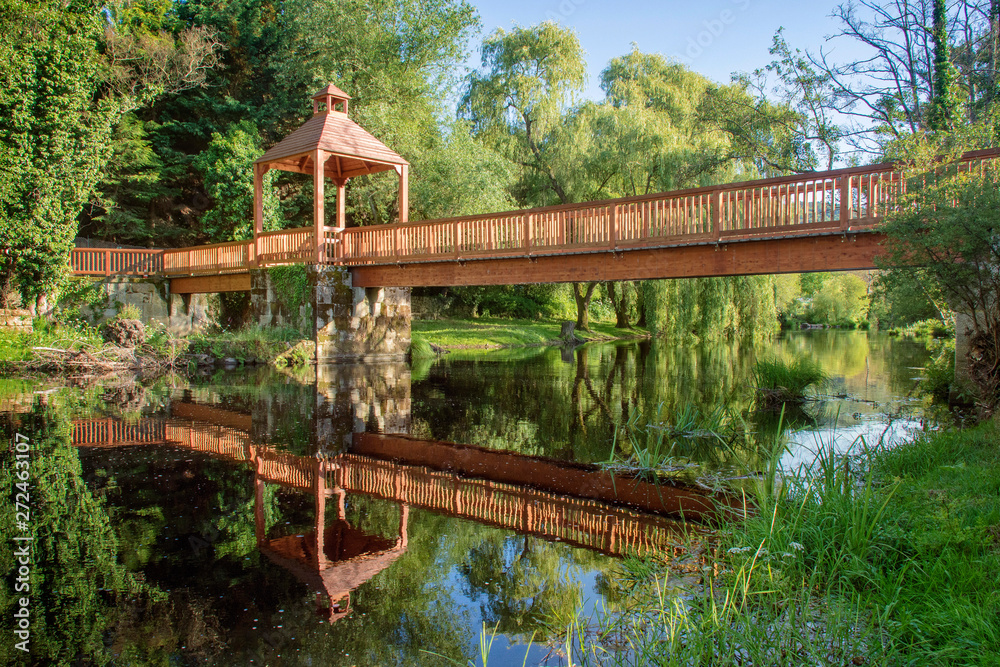 beautiful landscape of an old wooden bridge reflected in the river beautiful landscape of an old wooden bridge reflected in the river