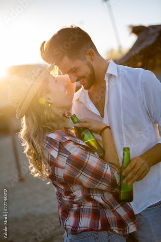 Happy young couple drinking beer and having fun at the beach