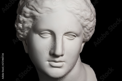 Gypsum copy of ancient statue Venus head isolated on black background. Plaster sculpture woman face.