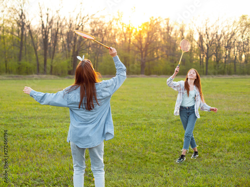 Two young women play badminton outdoors