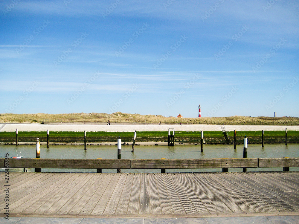 Promenade ensoleillée le long du chenal de Nieuport, phare à l'horizon Promenade ensoleillée le long du chenal de Nieuport, phare à l'horizon