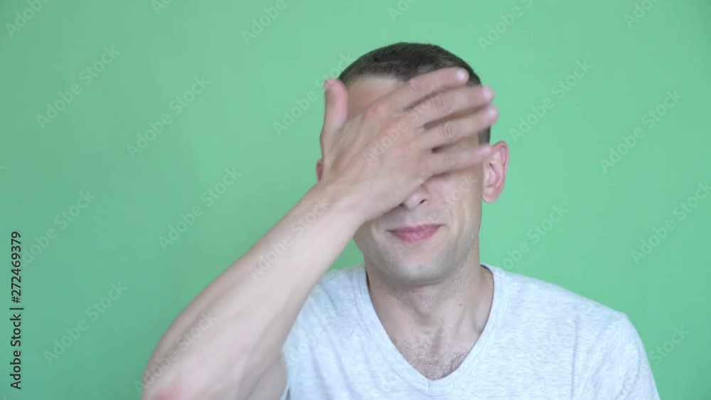 Portrait of a young man on a green background. he beats himself with irritation with his hand, palm over his forehead. he is unhappy and in a rage. Portrait of a young man on a green background. he beats himself with irritation with his hand, palm over his forehead. he is unhappy and in a rage.