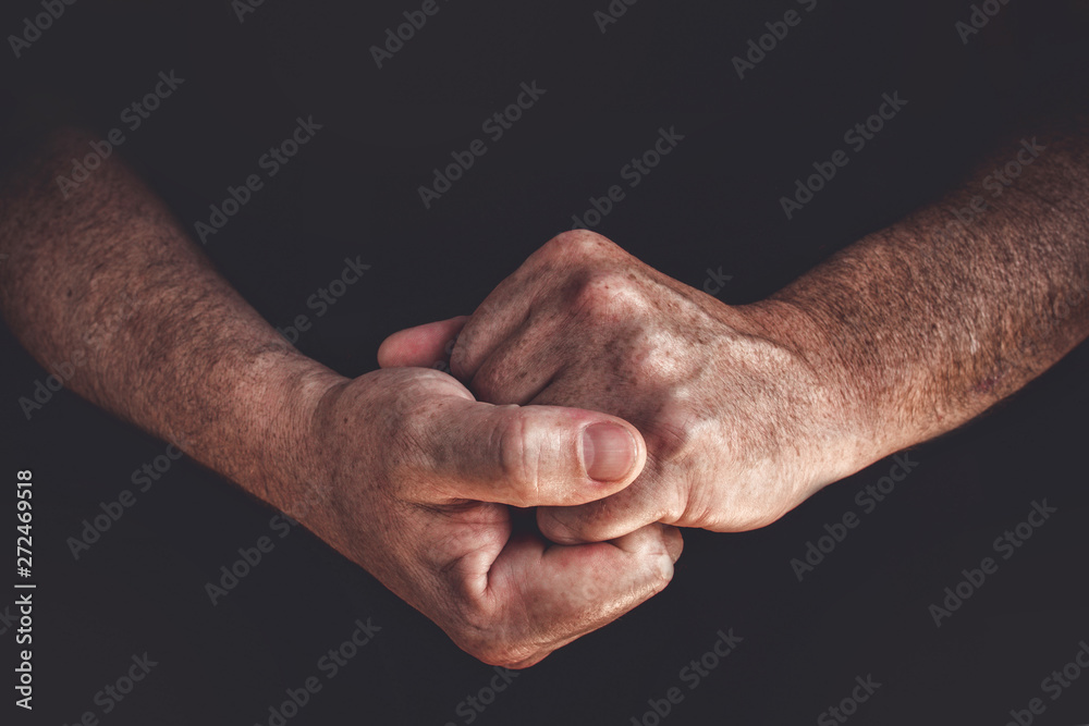 Fototapeta premium Hands of an elderly man worker closeup on a black background