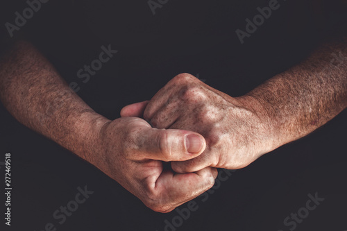Hands of an elderly man worker closeup on a black background