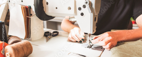 Bespoke service. Cropped shot of seamstress sewing clothes and threading needle. photo