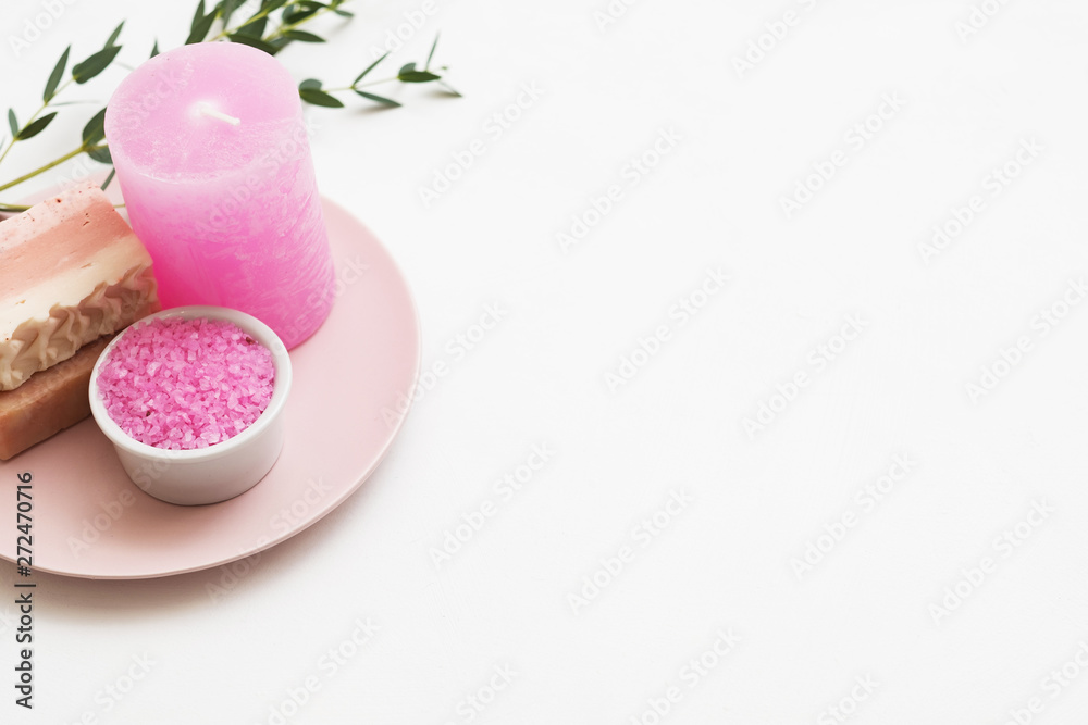 Spa aroma therapy. Flat lay of pink bath salt, handmade soap, candle and eucalyptus on plate. White background. Copy space.