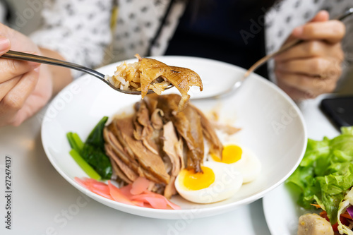 woman holding sliced roasted duck meat on spoon  ready to eat