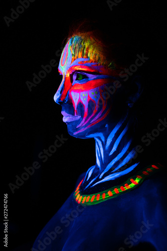 Fototapete Close-up side Portrait of Young naked bodyarted woman in blue glowing ultraviolet paint and Yellow eye lenses