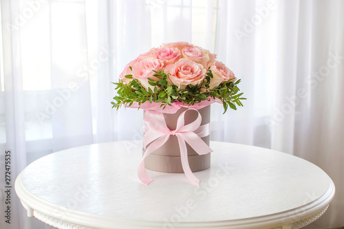 Beautiful bouquet of pink roses in a festive round box on a white table. Gift for holiday, birthday, Wedding, Mother's Day, Valentine's day, Women's Day.  Flowers in a hat box. photo