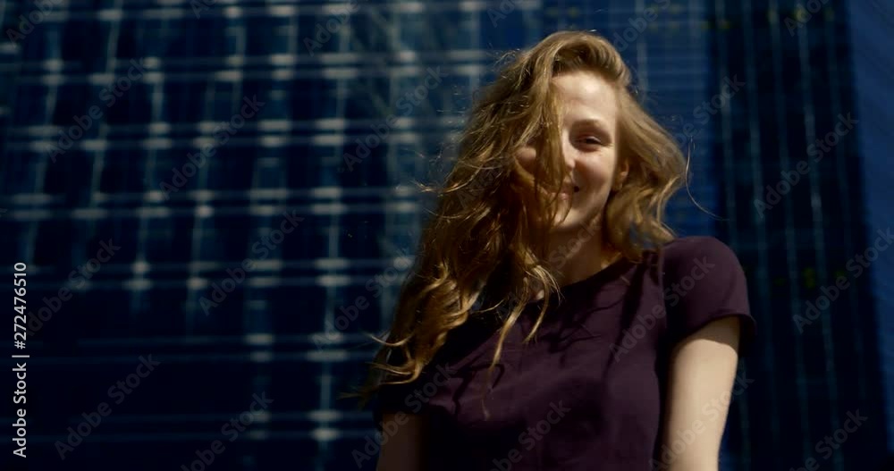 coquettish woman with light red hair is grimacing in front of camera on urban background coquettish woman with light red hair is grimacing in front of camera on urban background