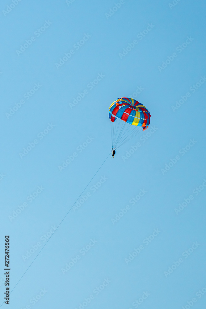 The operated parachute flies in high in the blue sky The operated parachute flies in high in the blue sky