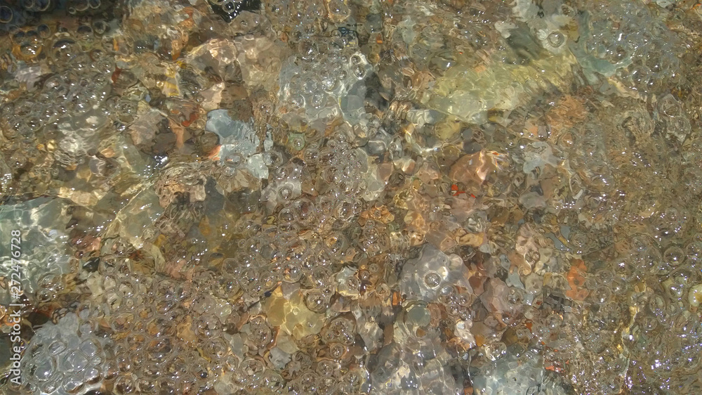 Water bubbles in the waves of the lake. Background water with pebbles for rest, travel, vocation. Image.