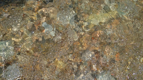 Water bubbles in the waves of the lake. Background water with pebbles for rest, travel, vocation. Image.