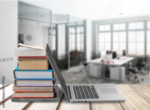 Stack of books with laptop on table