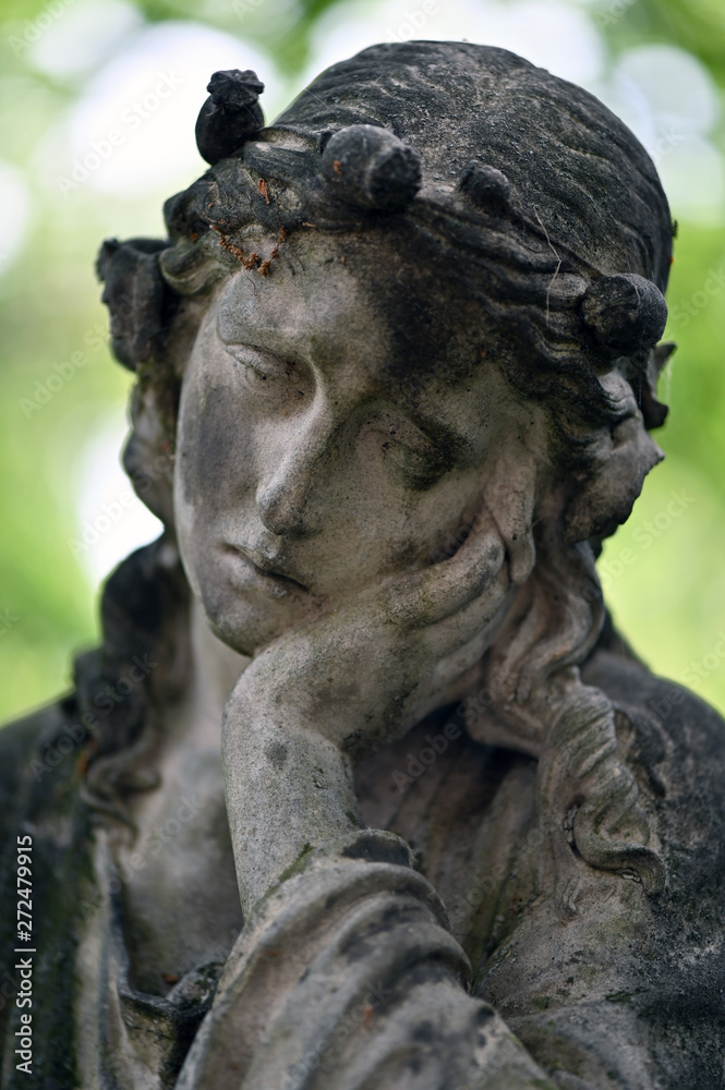 A weathered sandstone sculpture of a grieving angel. A weathered sandstone sculpture of a grieving angel.
