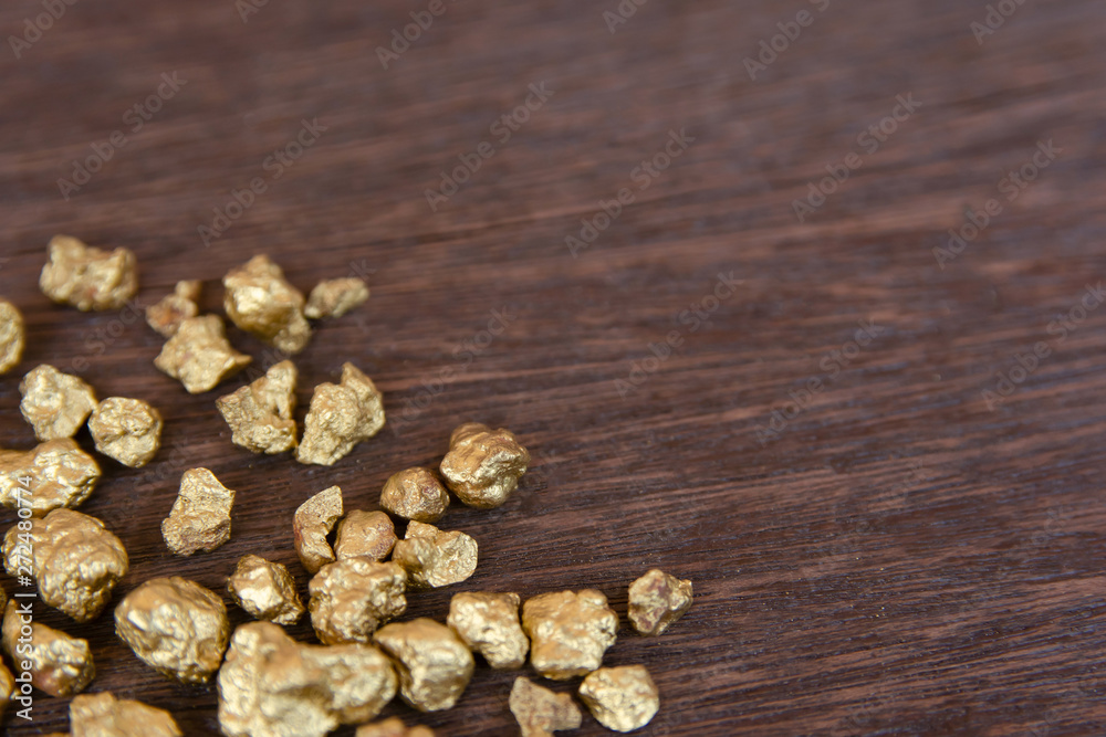 mound of gold nugget on dark wood background mound of gold nugget on dark wood background