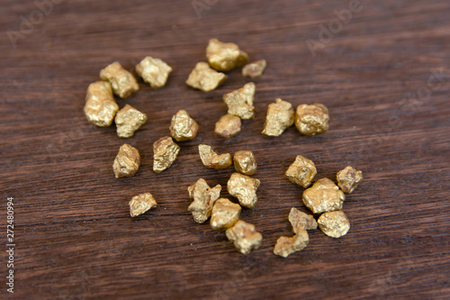 mound of gold nugget on dark wood background