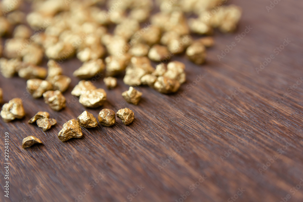 mound of gold nugget on dark wood background