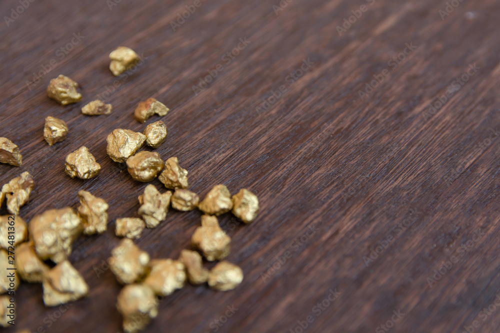 mound of gold nugget on dark wood background mound of gold nugget on dark wood background