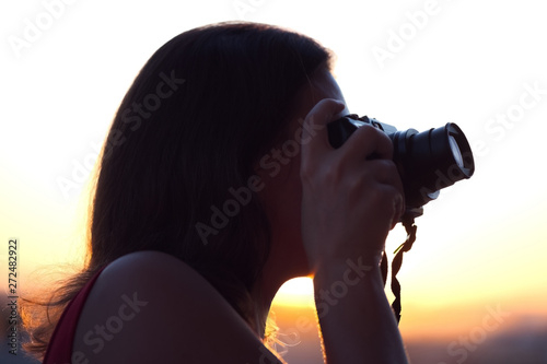 Silhouette of girl photographer taking picture on compact camera on the sunset background. photo