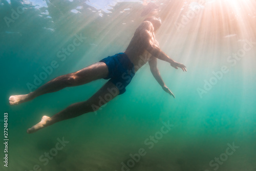 Man rises to surface to breathe while diving swimming in shallow photo