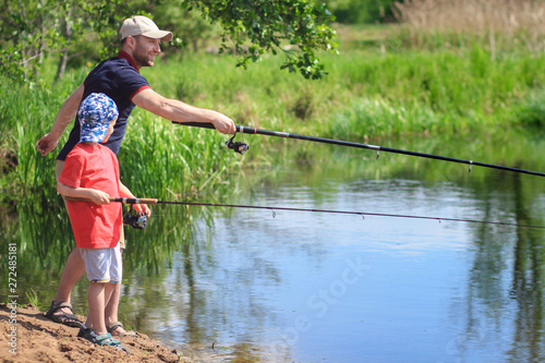 Family fishing. Father and son with spinning on riverbank. Active leisure on outdoor with family