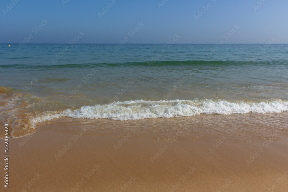 Soft wave ocean on golden sandy beach, background, Algarve, Portugal