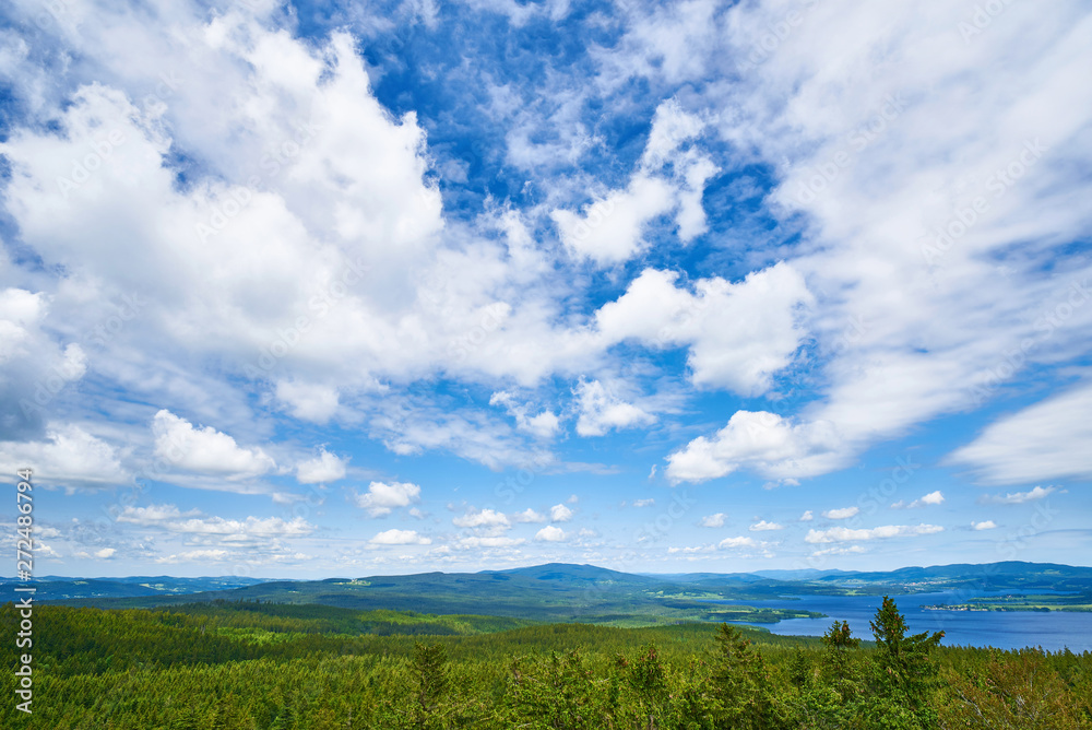 Blue sky with white clouds over the mountaneous landscape of Šumava nature preserve. View from lookout tower in castle ruins of Vítkův hrádek. The Lipno Reservoir in the background. Czech republic. Blue sky with white clouds over the mountaneous landscape of Šumava nature preserve. View from lookout tower in castle ruins of Vítkův hrádek. The Lipno Reservoir in the background. Czech republic.