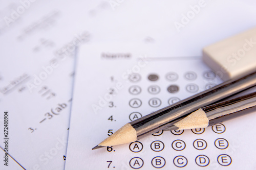 Pencil and eraser on answer sheets or Standardized test form with answers bubbled. multiple choice answer sheet .